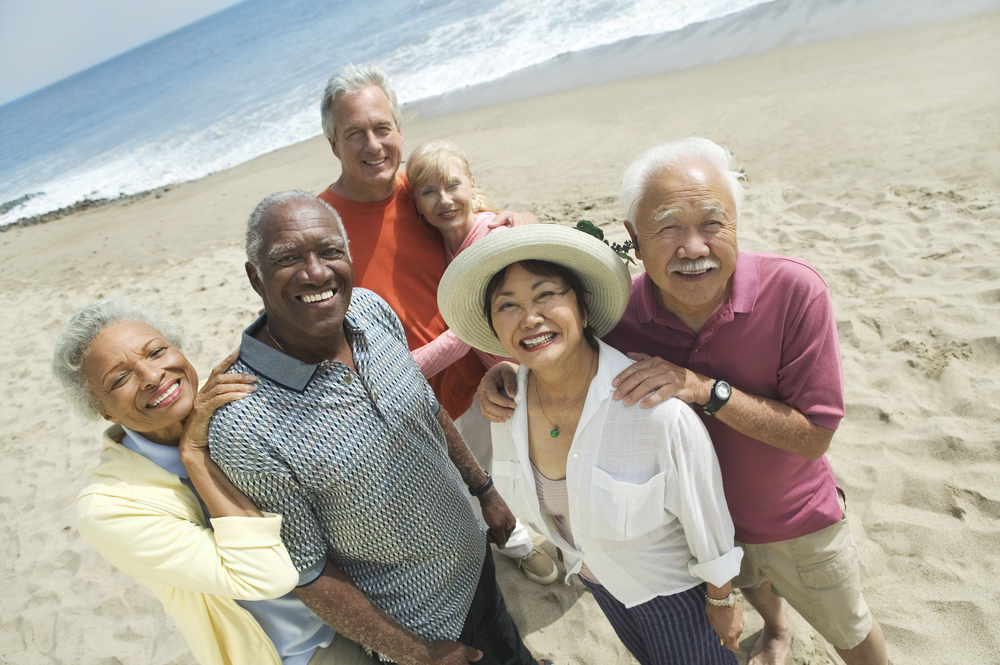 Group portrait of happy multiethnic couples smiling on the beach