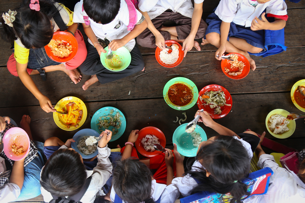 Children having lunch in asian school sitting on the floor