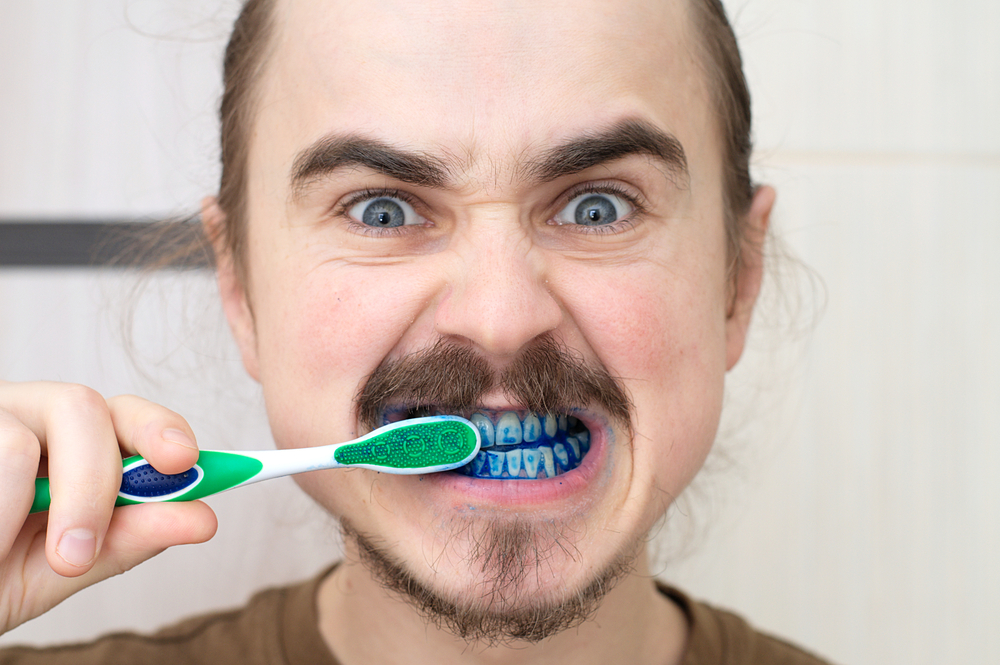 Man brushing his teeth and they've turned blue