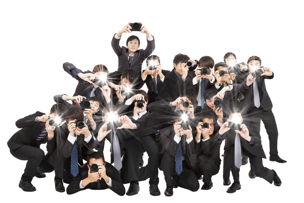 many photographers holding camera pointing to you and isolated on white