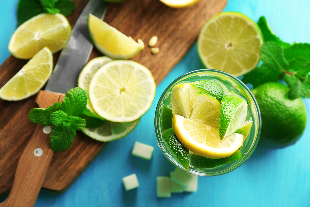 Fresh mojito drinks with lime, lemon and mint on blue background.