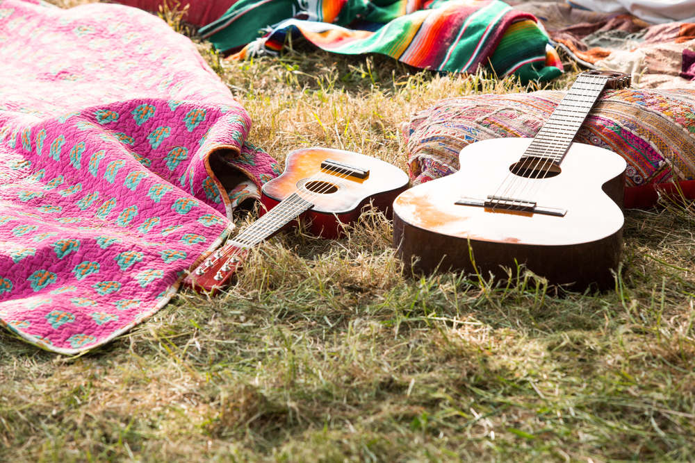 Two acoustic guitars and blankets on some grass.