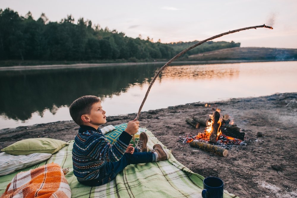 A boy roasting a marshmallow over a campfire.