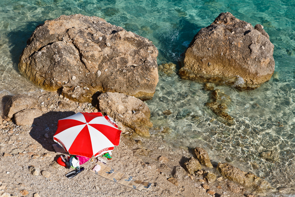 Red and White Parasol on the Rocky Beach in Croatia