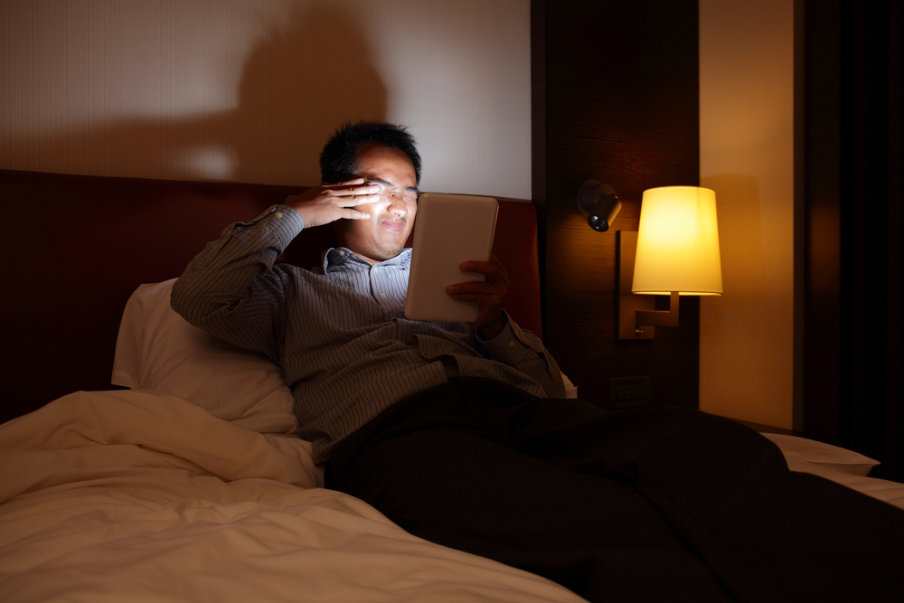 Tablet screens used by man in bed at night hurting his eyes