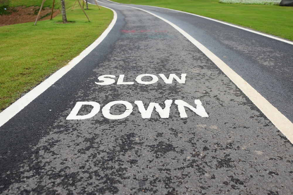 A slow down sign painted on a road