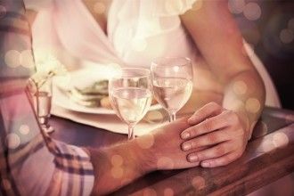 Couple holding hands over dinner and drinks