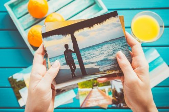 hands looking at vacation photos with orange juice on a table