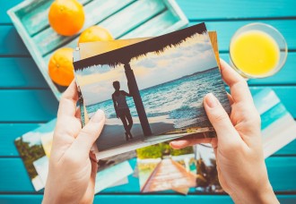 hands looking at vacation photos with orange juice on a table