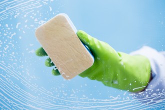 Green glove and soap wiping a window