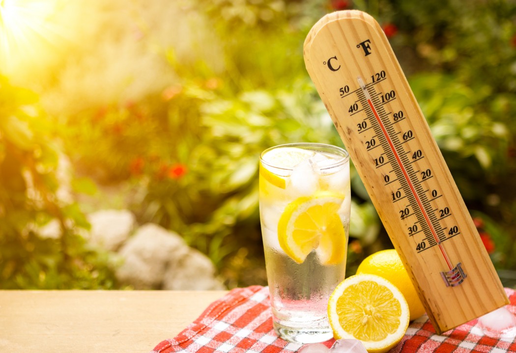 A thermometer showing the heat with glasses of lemonade.