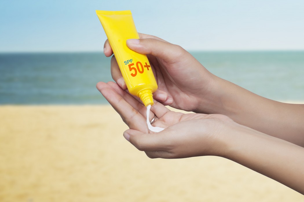 A woman putting on sunscreen.