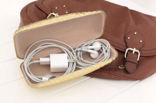 A glasses case used to hold a phone charger and ear buds. 