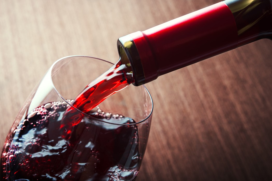 A closeup of red wine being poured into a glass.