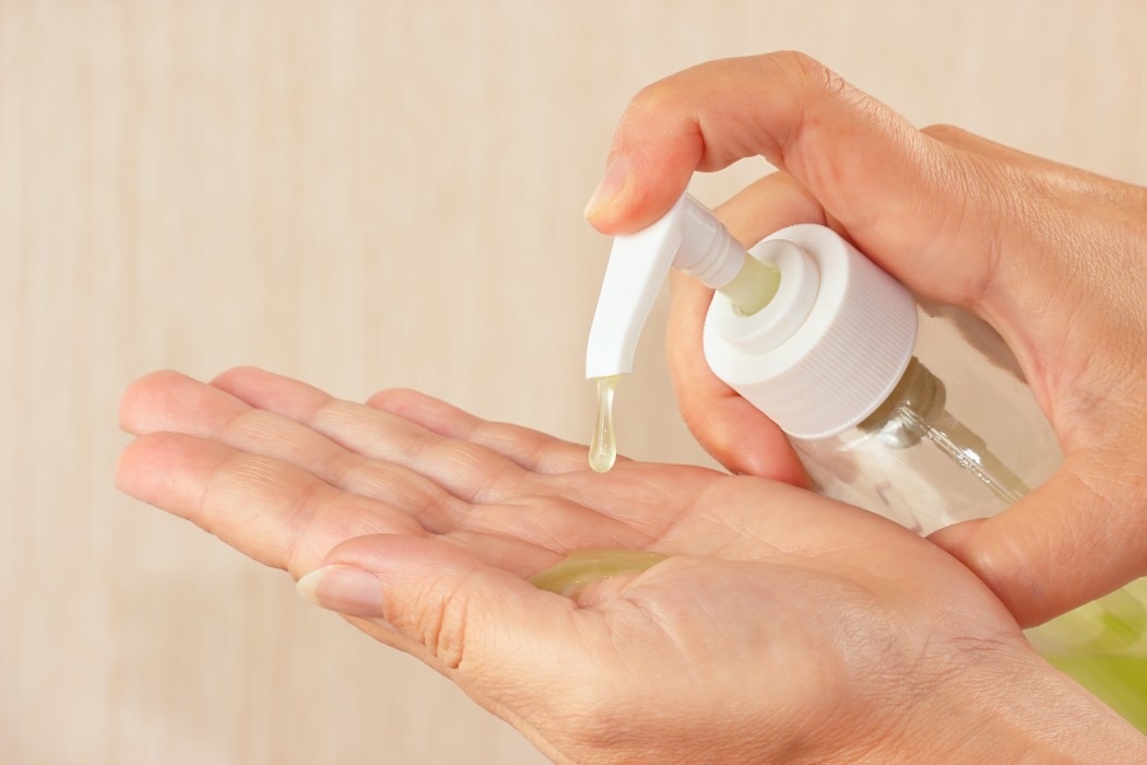 Female hands applying soap from a bottle.