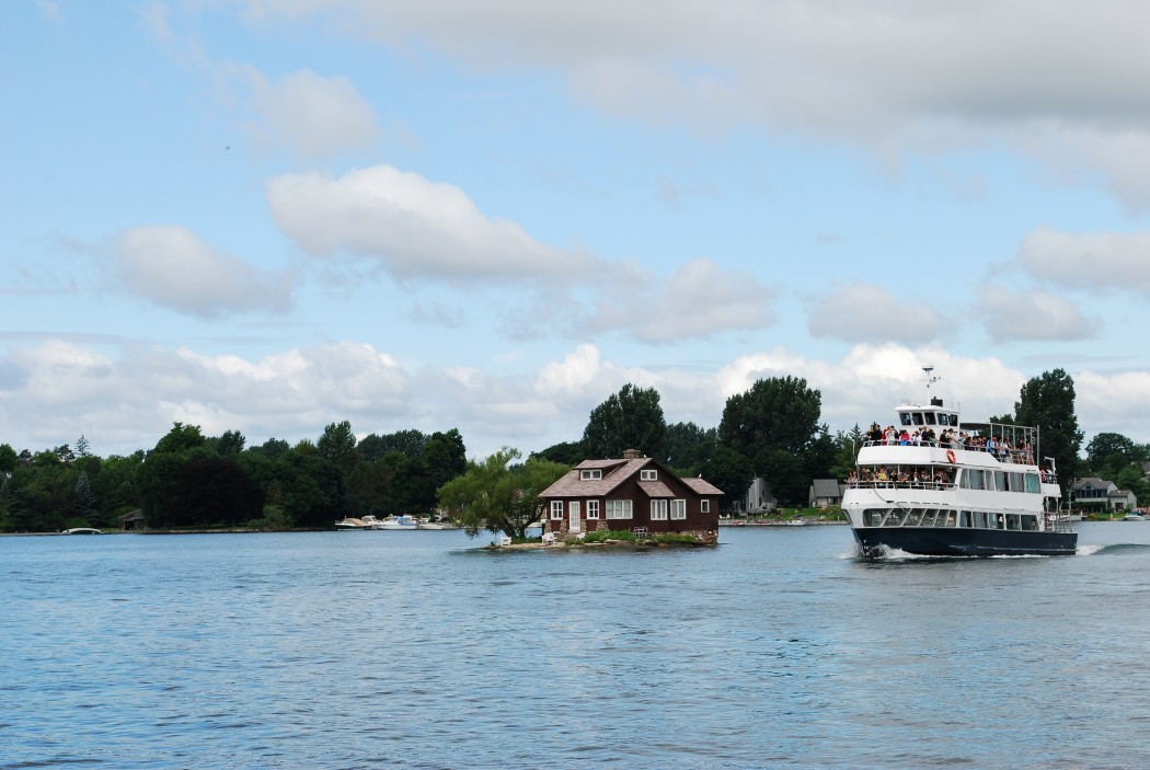 Photo of small house and cruise ship on the St. Lawrence River. USA - Canada border.
