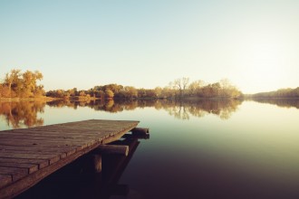 An autumn lake with trees and a dock.