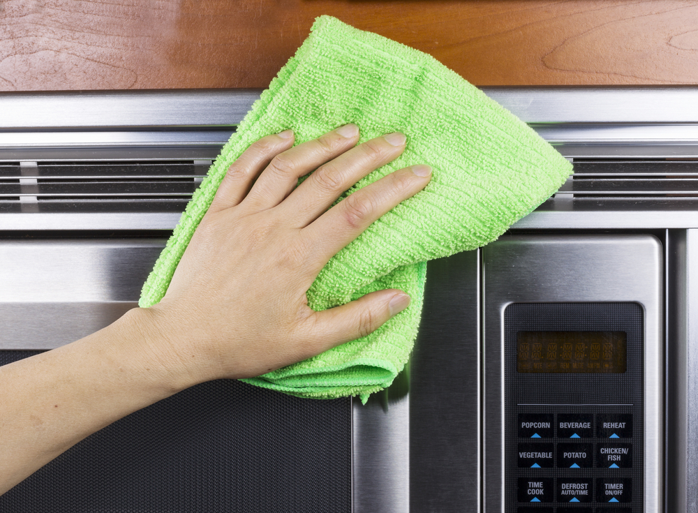Hand with microfiber rag cleaning vents of microwave oven