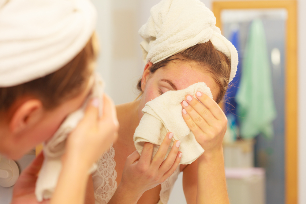 A woman cleaning her face with a wash cloth