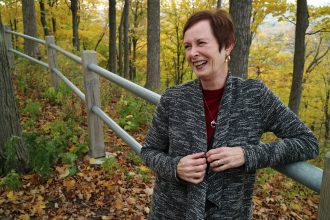A photo of a woman outside in fall foliage