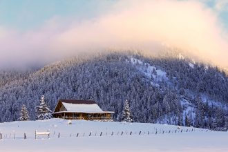 Winter sunset with a log cabin, Utah, USA.