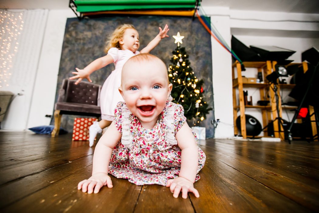 A baby and young girl with a Christmas tree