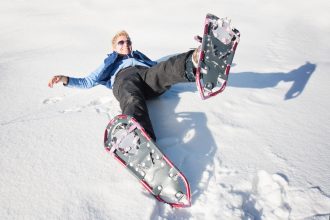 Woman playing in the snow with snowshoes on